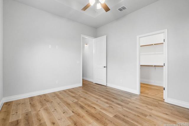 unfurnished bedroom with ceiling fan, a closet, a spacious closet, and light hardwood / wood-style flooring