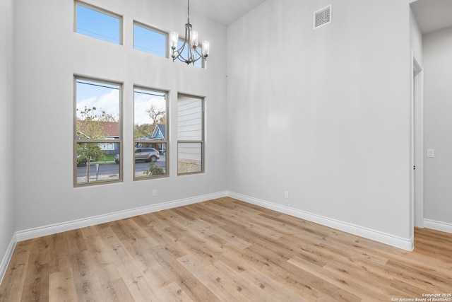 unfurnished room with a notable chandelier and light hardwood / wood-style flooring