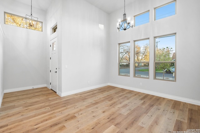 interior space featuring a notable chandelier, a towering ceiling, and light hardwood / wood-style flooring