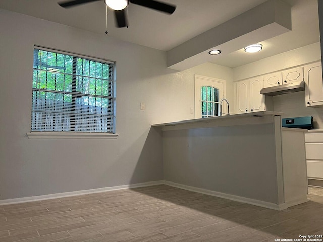 kitchen featuring white cabinets, light wood-type flooring, ceiling fan, and sink