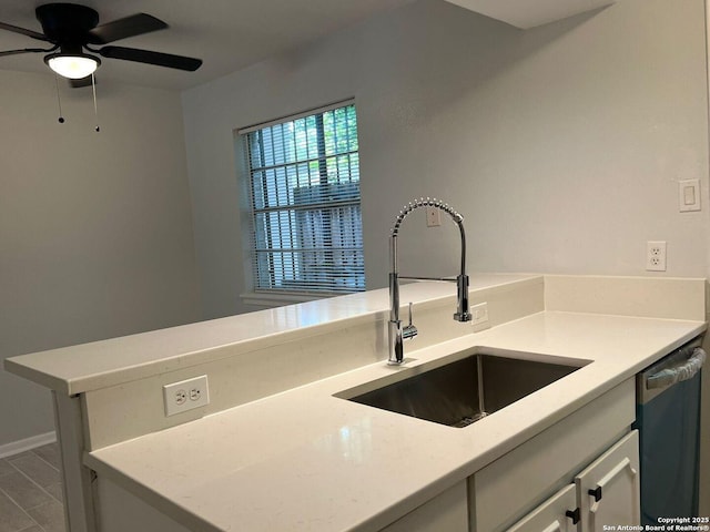 kitchen with sink, stainless steel dishwasher, ceiling fan, light stone counters, and kitchen peninsula