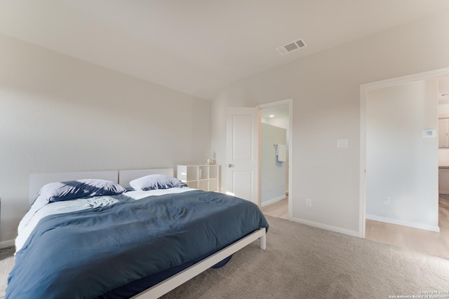 carpeted bedroom with connected bathroom and vaulted ceiling