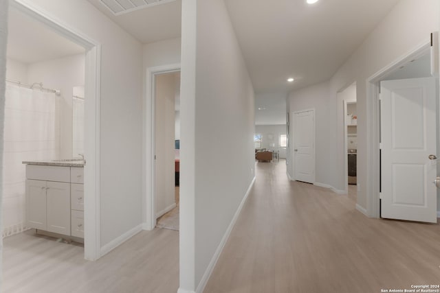 corridor with light hardwood / wood-style flooring and sink