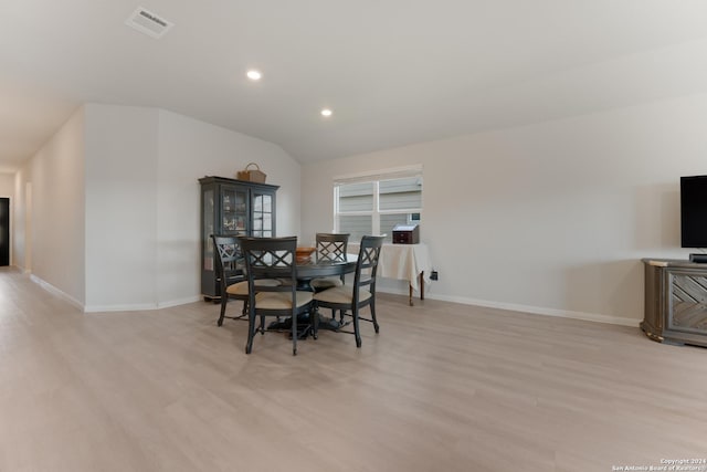 dining space with light wood-type flooring and vaulted ceiling