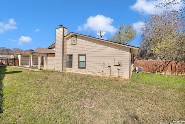 rear view of house with cooling unit and a yard