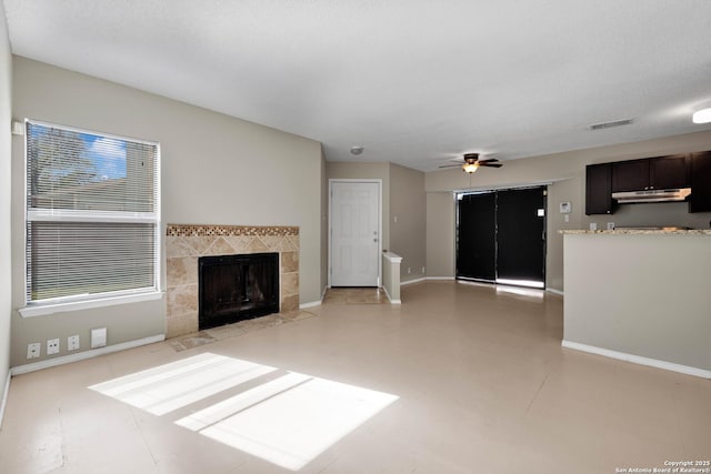 unfurnished living room with a tile fireplace and ceiling fan