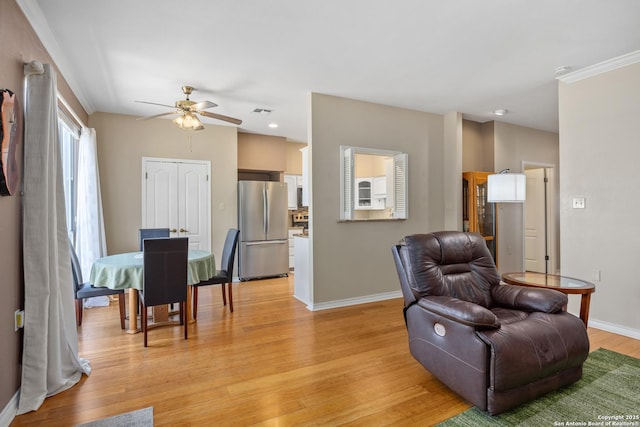 living room with light hardwood / wood-style floors, ceiling fan, and crown molding