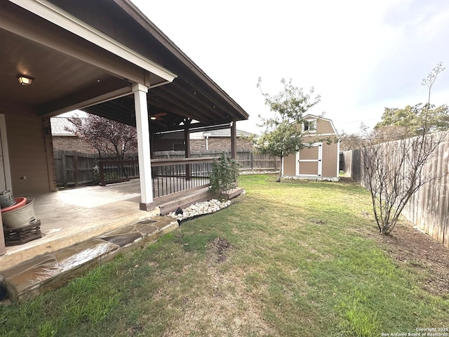 view of yard with a storage unit, ceiling fan, a patio area, and a wooden deck