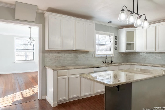 kitchen featuring white cabinets, light stone counters, ornamental molding, and sink