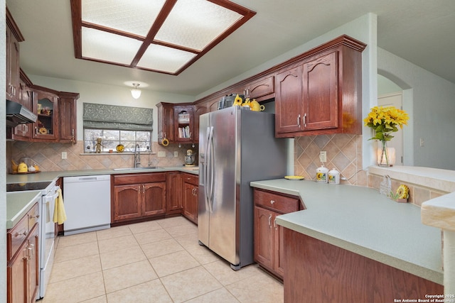 kitchen with decorative backsplash, light tile patterned floors, white appliances, and sink