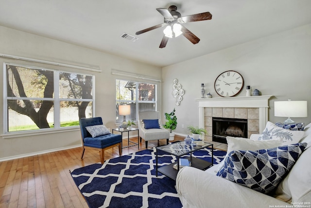 living room featuring ceiling fan, wood-type flooring, and a tiled fireplace