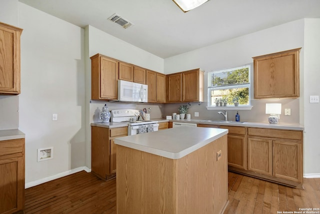 kitchen featuring hardwood / wood-style flooring, white appliances, a center island, and sink