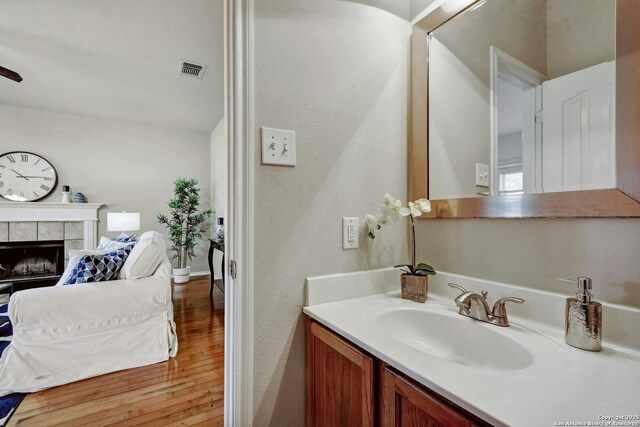 bathroom with vanity, hardwood / wood-style flooring, and a fireplace