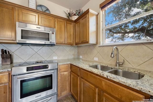 kitchen with stove, tasteful backsplash, light stone counters, and sink