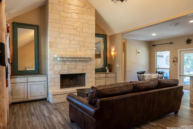 living room with a stone fireplace, dark hardwood / wood-style floors, and vaulted ceiling