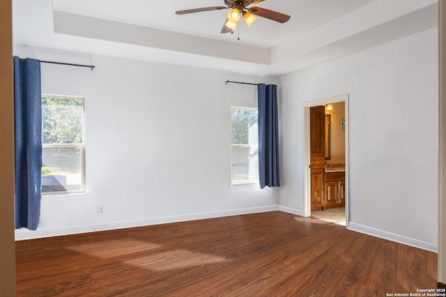 unfurnished room featuring hardwood / wood-style floors, ceiling fan, and a raised ceiling