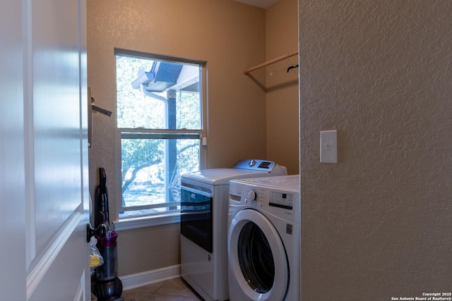 clothes washing area with a wealth of natural light, light tile patterned floors, and washer and clothes dryer