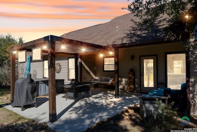 back house at dusk with outdoor lounge area, a patio, and a hot tub