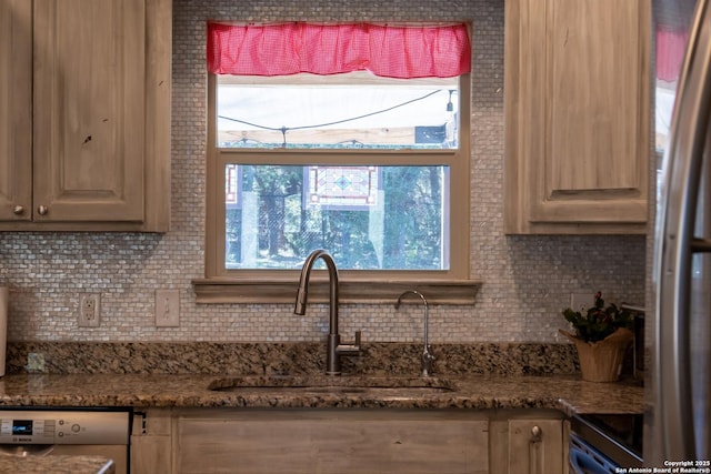 kitchen featuring decorative backsplash, range, sink, and dishwashing machine