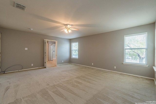 unfurnished room with ceiling fan, a wealth of natural light, and light colored carpet