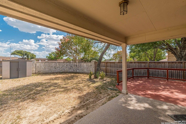 view of yard with a deck, a storage shed, and a patio area