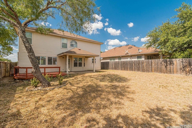 rear view of property featuring a yard and a deck