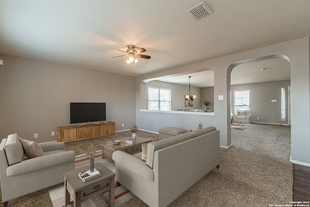 living room with ceiling fan with notable chandelier and plenty of natural light