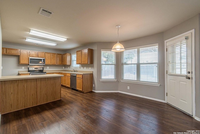 kitchen featuring appliances with stainless steel finishes, dark hardwood / wood-style flooring, pendant lighting, and kitchen peninsula