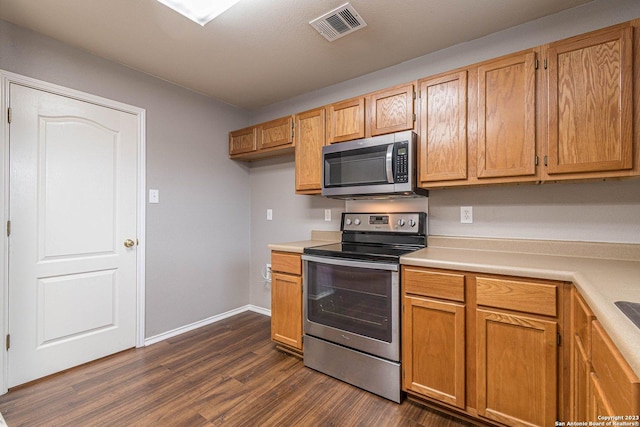 kitchen with appliances with stainless steel finishes and dark hardwood / wood-style floors