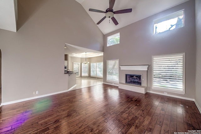 unfurnished living room featuring hardwood / wood-style flooring, ceiling fan, a fireplace, and high vaulted ceiling