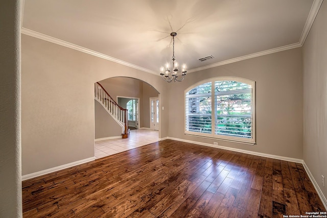 spare room featuring light wood-type flooring, ornamental molding, and a chandelier