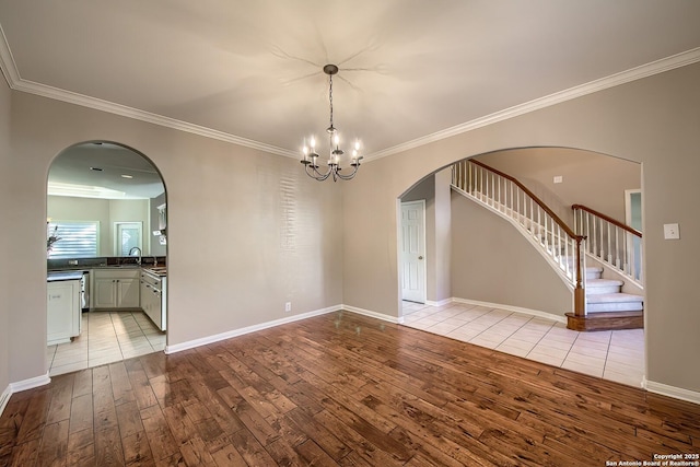 empty room with sink, light hardwood / wood-style floors, a notable chandelier, and ornamental molding