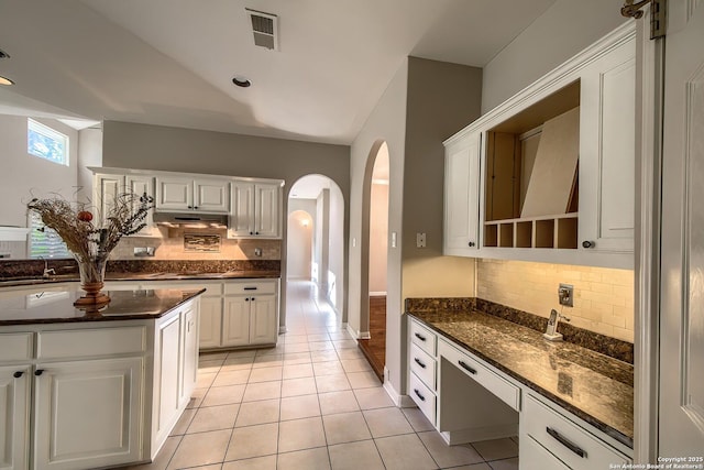 kitchen featuring white cabinets, light tile patterned floors, decorative backsplash, and dark stone counters