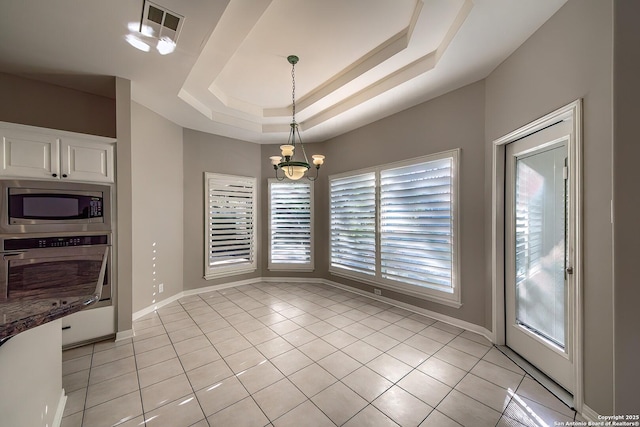 dining room with a tray ceiling, light tile patterned flooring, and a chandelier