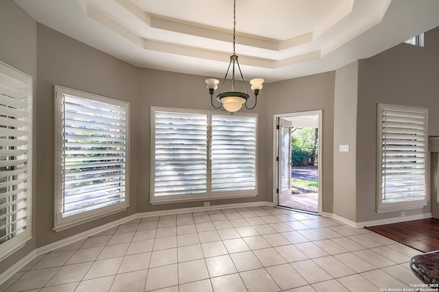 unfurnished dining area featuring a raised ceiling, light tile patterned floors, and a notable chandelier