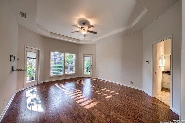 spare room featuring a tray ceiling, dark hardwood / wood-style floors, and ceiling fan