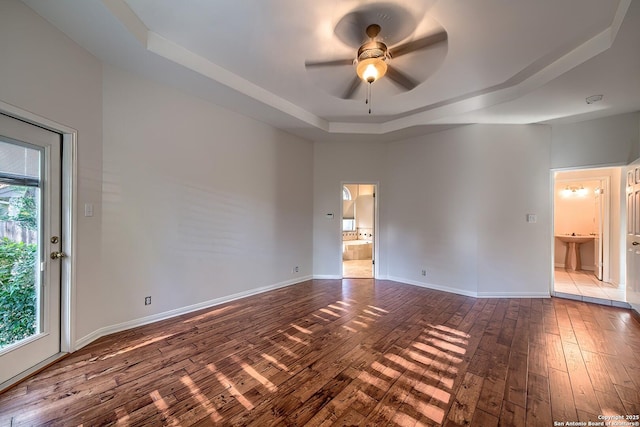 empty room with a raised ceiling, ceiling fan, sink, and hardwood / wood-style flooring