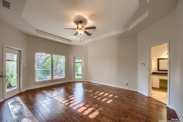 unfurnished room featuring dark hardwood / wood-style flooring, a raised ceiling, and ceiling fan