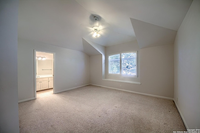 additional living space with light colored carpet and vaulted ceiling