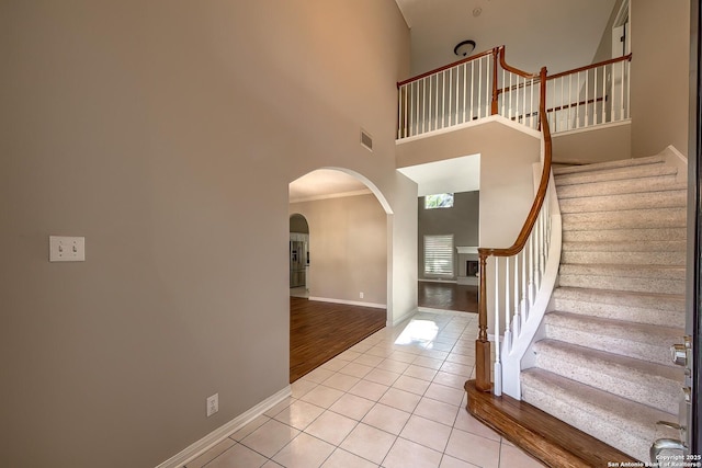 tiled entryway with a towering ceiling and ornamental molding