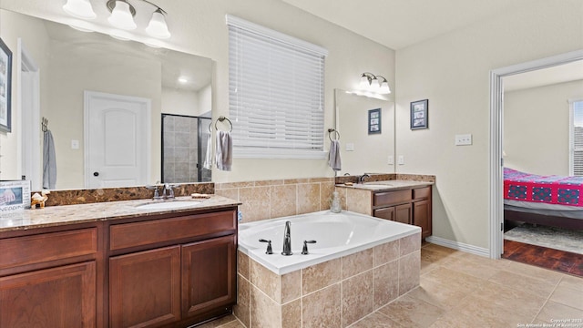 bathroom featuring tile patterned flooring, a relaxing tiled tub, and vanity