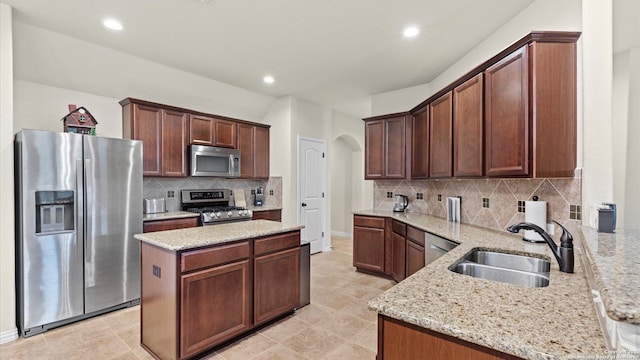 kitchen with kitchen peninsula, light stone counters, sink, and stainless steel appliances