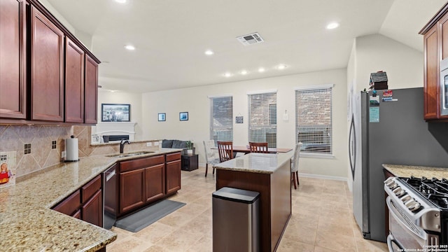 kitchen with stainless steel appliances, light stone counters, tasteful backsplash, and sink