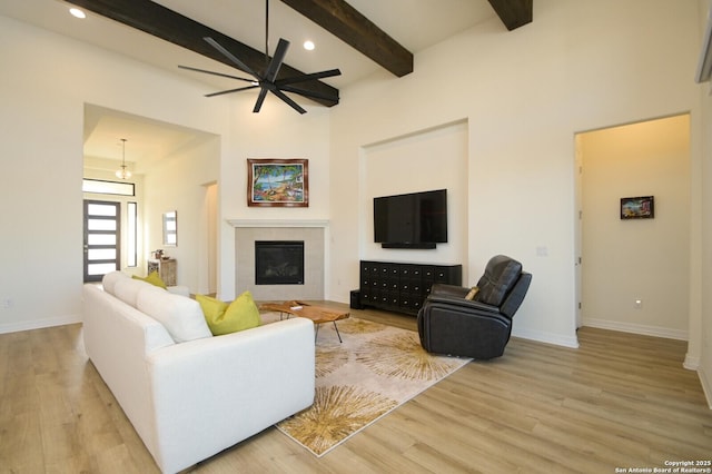 living room featuring ceiling fan, beam ceiling, and light wood-type flooring