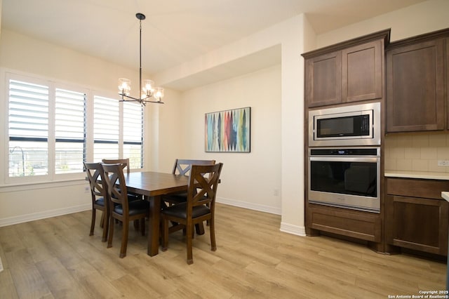 dining room with light hardwood / wood-style floors and an inviting chandelier