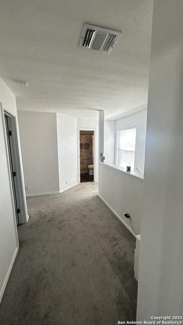 unfurnished room with carpet flooring and a textured ceiling