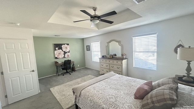 bedroom featuring ceiling fan, light colored carpet, and a tray ceiling