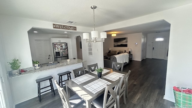 dining room with dark hardwood / wood-style flooring, a chandelier, a textured ceiling, and sink