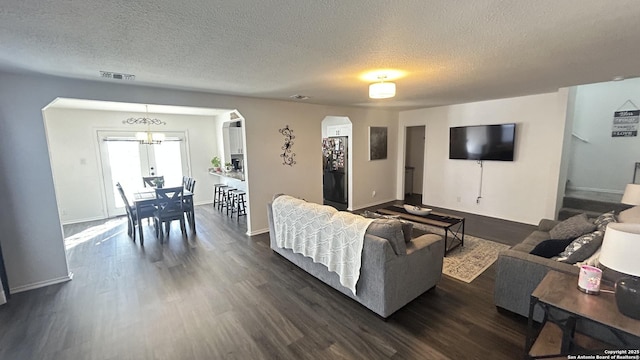 living room with a notable chandelier, dark hardwood / wood-style floors, and a textured ceiling