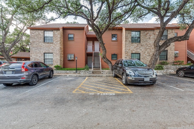 view of building exterior featuring uncovered parking and stairs